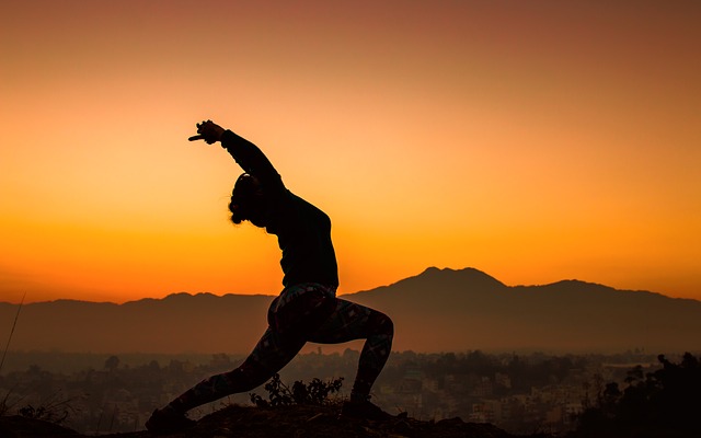 a woman does yoga against mountains during a sunset